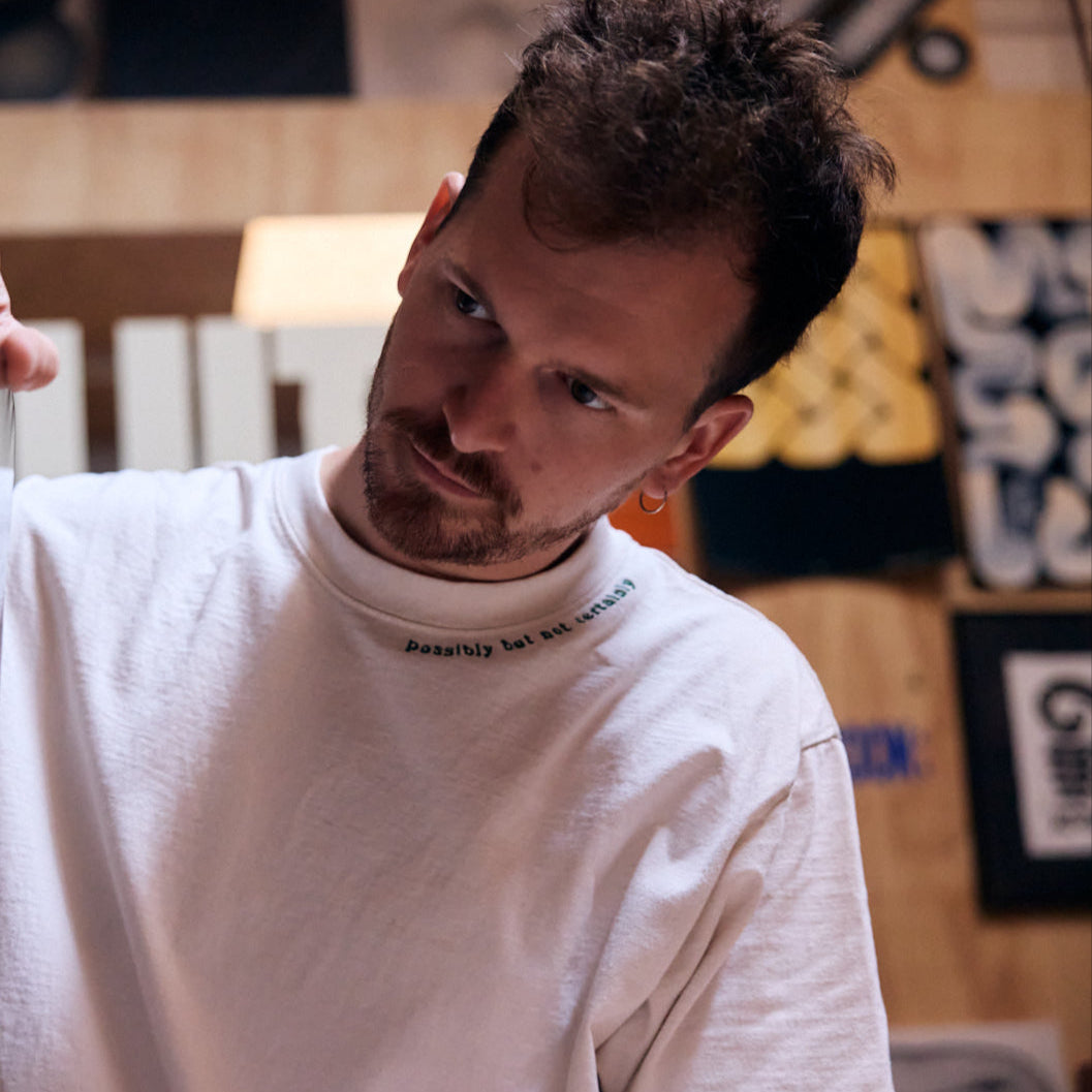 Man wearing a white long-sleeve shirt in an indoor setting with blurred background